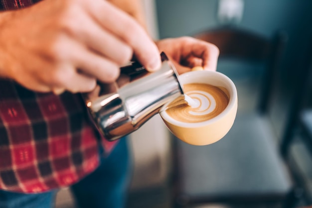 Professionele Barista die heet melkschuim giet en koffie latte art maakt