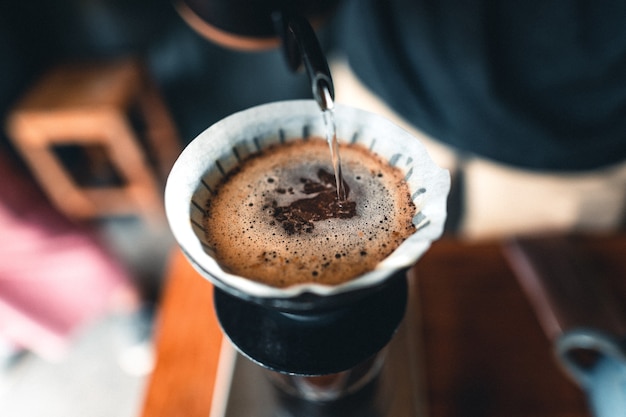 Foto professionele barista die koffie bereidt, giet over koffiezetapparaat en druppelketel