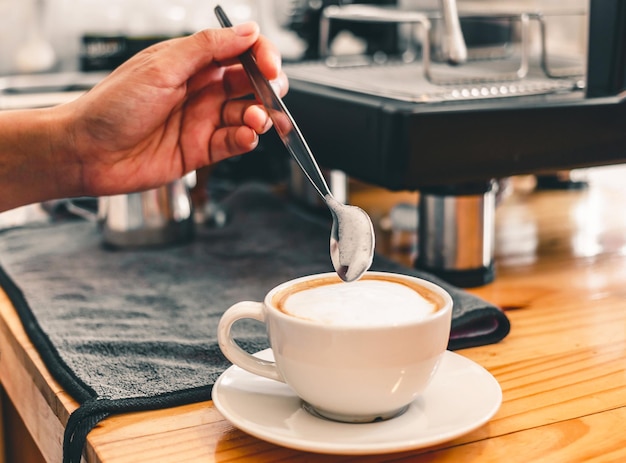 Professionele barista's gebruiken roestvrijstalen lepels om melkschuim glad te strijken in een hete koffiekop