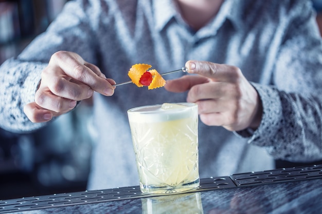 Professionele barman die cocktaildrank maakt en versierd met fruit.