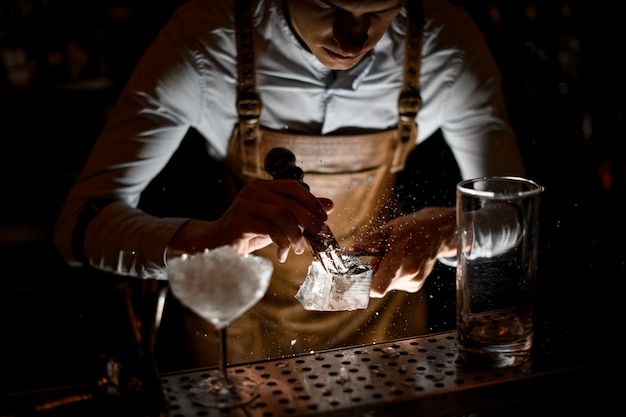 Professionele barman in lederen schort die een verpletterde met een speciale vork