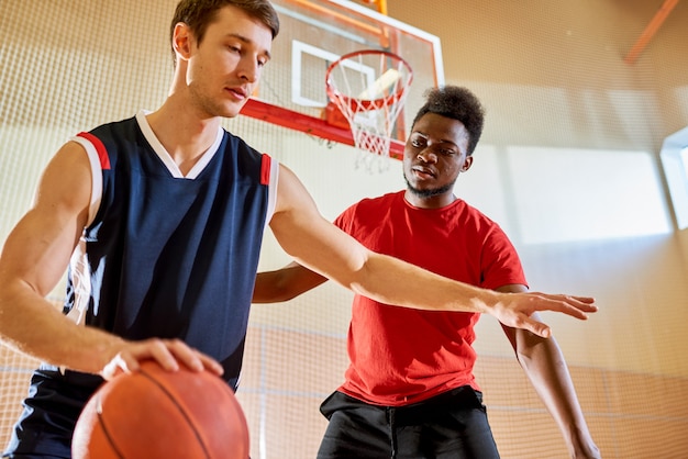 Professionele basketbalspeler die dichtbij de mand van de concurrent dribbelt