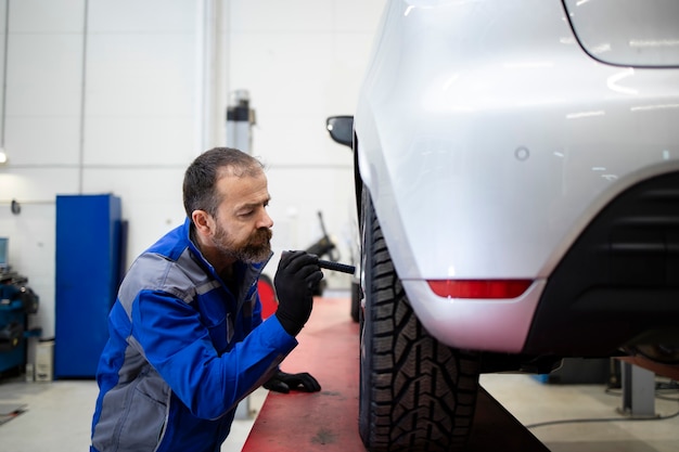 Professionele bebaarde blanke automonteur van middelbare leeftijd die visuele inspectie van remvoeringen en schijven doet.