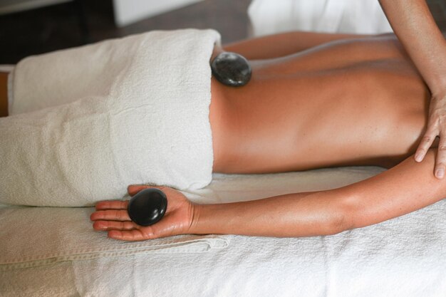 Professionele blanke vrouwelijke fysiotherapeut masseuse die stenenmassage op de ruggraat uitvoert