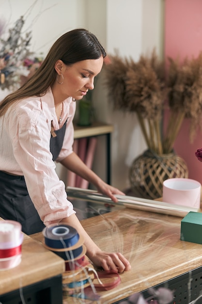 Professionele bloemist jonge vrouw doet boeketten bij bloemenwinkel