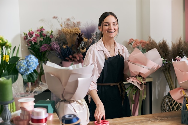 Professionele bloemist jonge vrouw doet boeketten bij bloemenwinkel