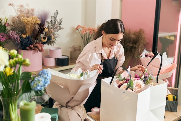 Professionele bloemist jonge vrouw doet boeketten bij bloemenwinkel