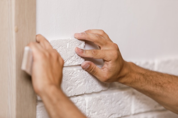 Professionele bouwer die decoratieve tegels op muur lijmen. werknemer monteert decoratieve baksteen op de muur