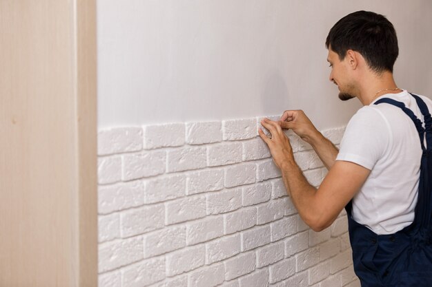 Professionele bouwer die decoratieve tegels op muur lijmen. werknemer monteert decoratieve baksteen op de muur