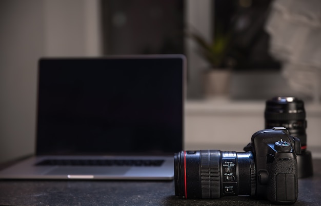 Professionele camera op een onscherpe achtergrond met een laptop. Het concept van het werken met foto's en video's.