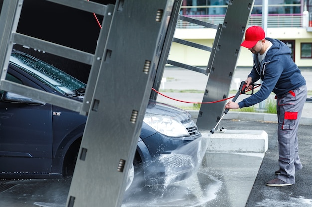 Professionele carwash werknemer wast de auto van de klant