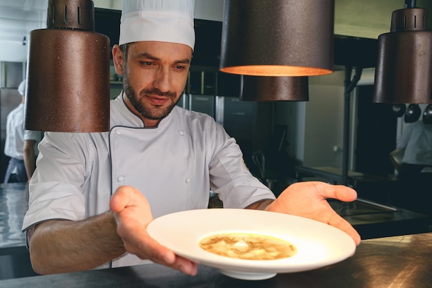 Professionele chef-kok controleert gerecht vlak voordat hij het aan de klant in het restaurant serveert