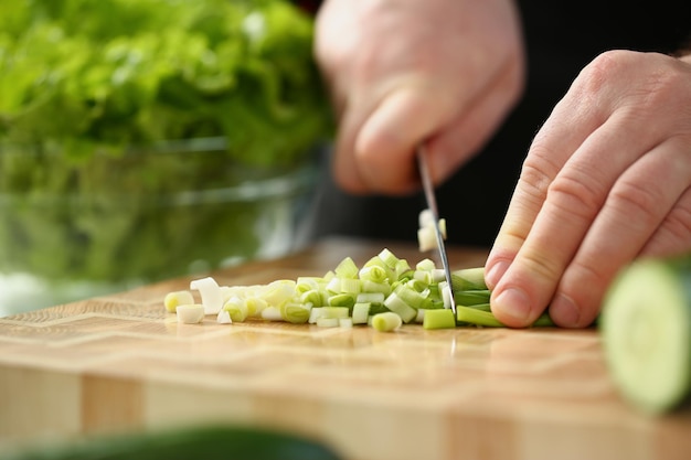 Professionele chef-kok gesneden lente-ui met scherp mes op snijplank