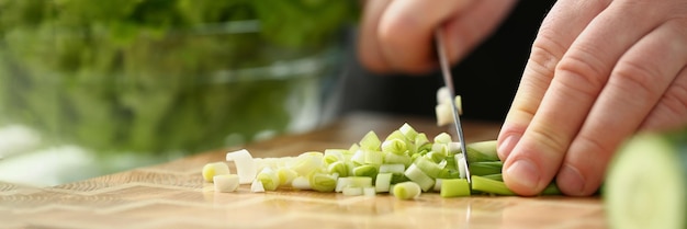 Professionele chef-kok gesneden lente-ui met scherp mes op snijplank