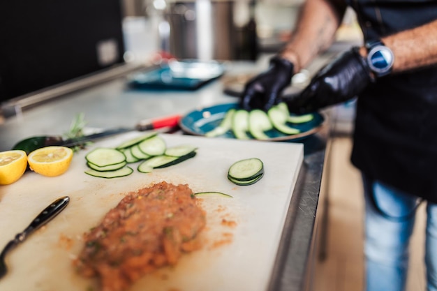 Professionele chef-kok in restaurantkeuken die heerlijke maaltijd met vlees en groenten bereidt.