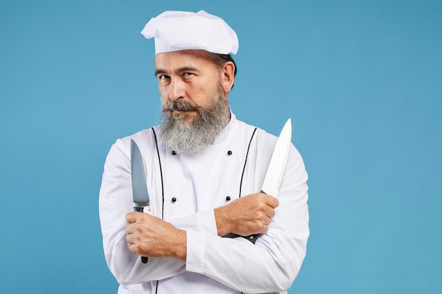 Foto professionele chef-kok met messen op blauw