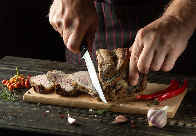 Professionele chef-kok snijdt gegrild rundvlees op een snijplank