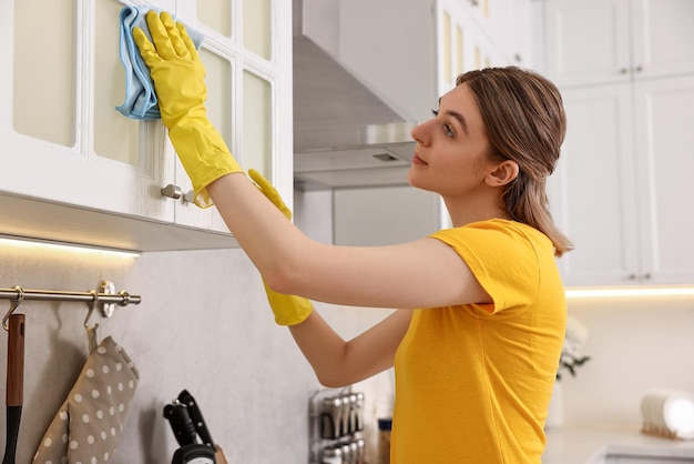 Professionele conciërge die uniform draagt en de keukenkast schoonmaakt