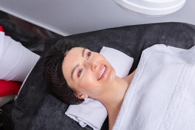 Professionele cosmetoloog die gezichtsmassage geeft aan een vrouw in een spa-salon.