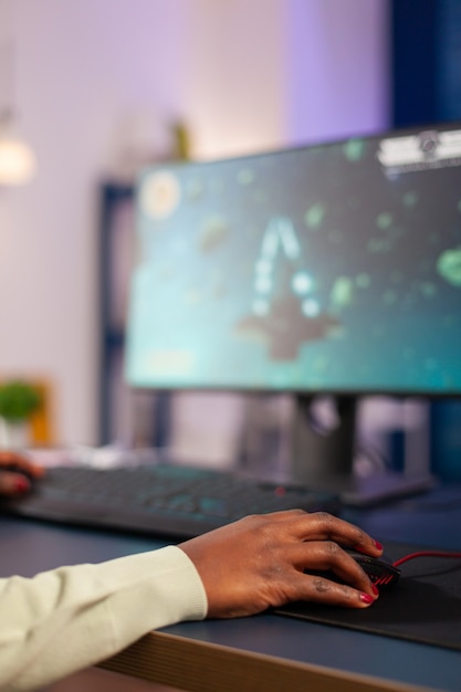 Professionele e-sport gamer die online games speelt in de huiskamer. Close up van Afrikaanse vrouw hand spelen online esport videogames space shooter met toetsenbord.