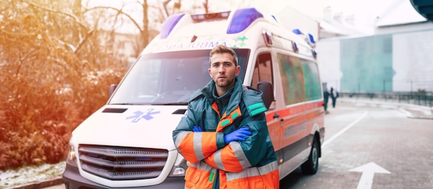 Professionele en zelfverzekerde jonge man arts met ambulance