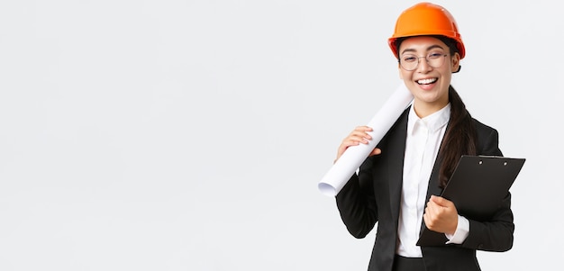 Professionele gelukkige Aziatische vrouwelijke architect bouwingenieur in helm en pak met...
