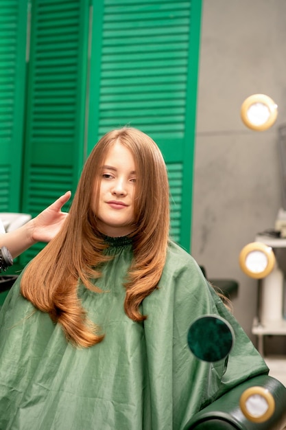 Professionele haarverzorging Jonge vrouw roodharig met lang haar die hairstyling krijgt in een schoonheidssalon