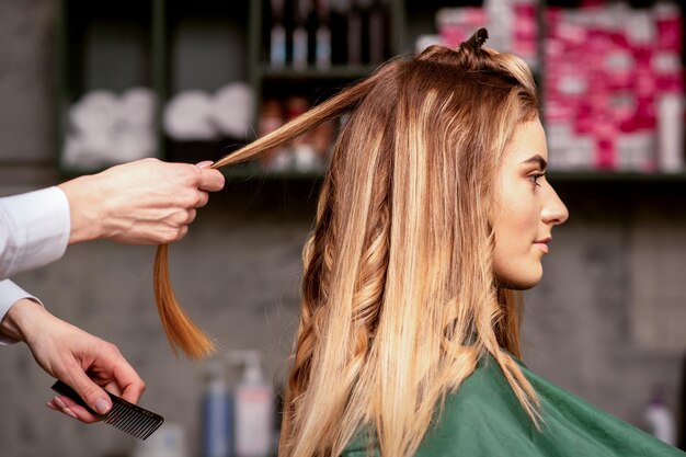 Professionele haarverzorging Mooie jonge blanke blonde vrouw met lang haar die hairstyling krijgt in een schoonheidssalon