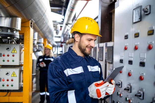 Professionele industriële elektricien in veiligheidswerkkleding die het stroomverbruik op de computer controleert