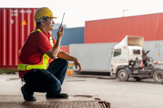 Professionele ingenieur containerlading voorman in helmen die zittend werken en walkie talkie gebruiken