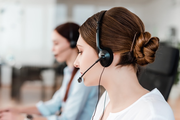 Professionele jonge beambte met een hoofdtelefoon die in een call centre beantwoordt