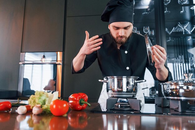 Professionele jonge chef-kok in uniform heeft een drukke dag in de keuken