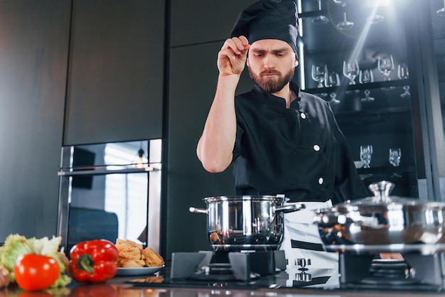 Professionele jonge chef-kok in uniform heeft een drukke dag in de keuken