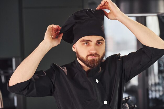 Foto professionele jonge chef-kok in uniform staande op de keuken