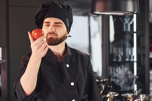 Professionele jonge chef-kok in uniform staande op de keuken