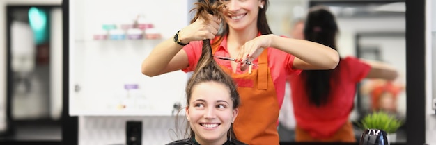 Professionele kapper die haarlok vasthoudt en gaat knippen met een schaar