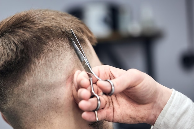 Professionele kapper die kapsel maakt voor jonge man bij kapperszaak