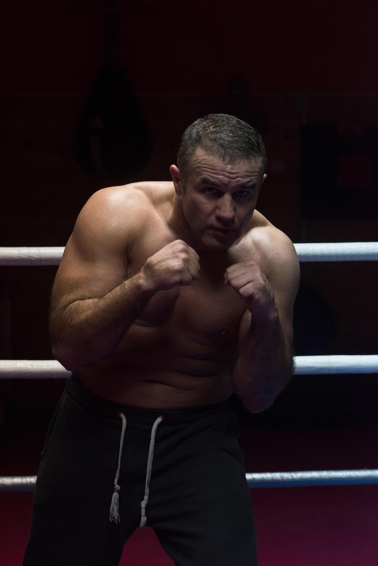 Foto professionele kickbokser met handen in vechtsportpositietraining voor het gevecht in de trainingsring