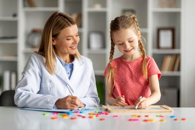 Foto professionele kinderpsycholoog dame die therapiesessie heeft met schattig klein meisje