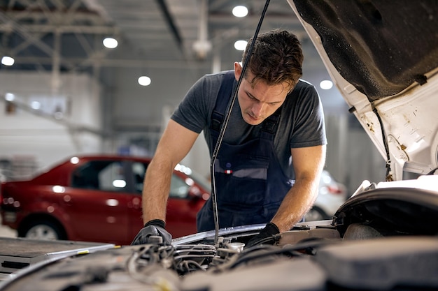 Professionele knappe monteur in uniform werkt in autoservice, autoreparatieonderhoud en mensen...