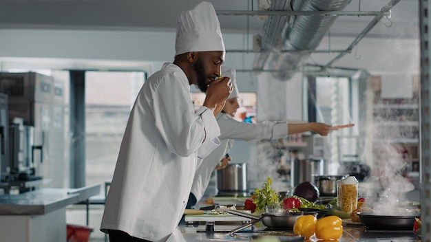 Professionele kok die een smakelijke maaltijd bereidt met rozemarijnbladeren, met behulp van rauwe groene plant om een heerlijk gastronomisch gerecht te maken. Authentieke chef-kok die vegetarisch voedsel in pan op keukenfornuis kookt.