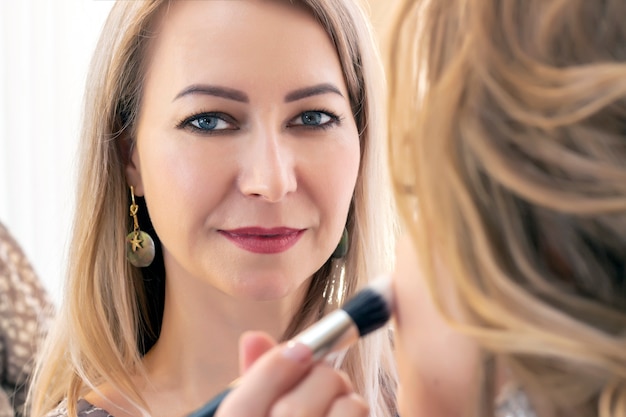 Professionele make-up artiest werken met client in salon.