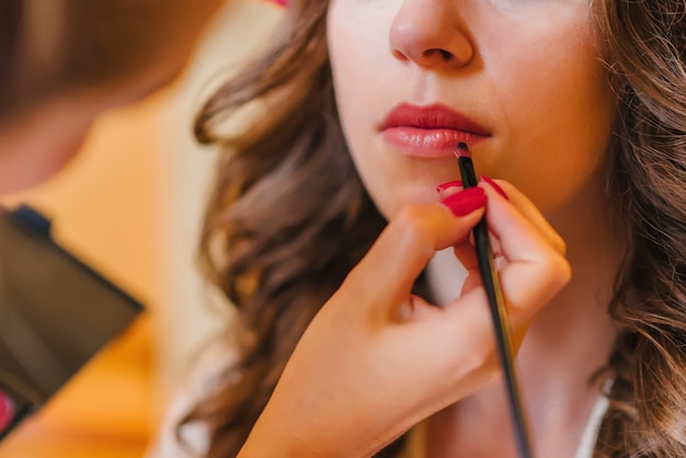 Professionele make-up artist krijgt lippenstift op haar lippen met borstel