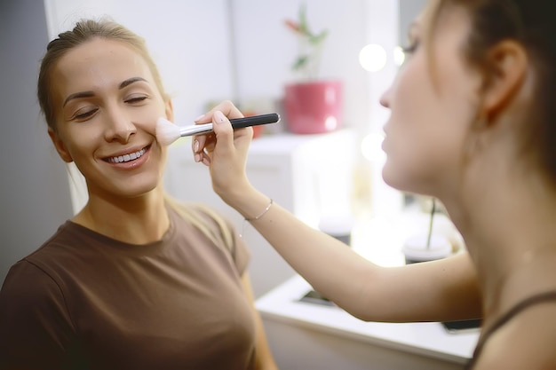 professionele make-up in de schoonheidssalon / meester maakt een professionele frisse zomermake-up van een mooi model in de salon