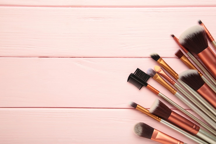 Foto professionele make-up kwasten op roze houten achtergrond. bovenaanzicht
