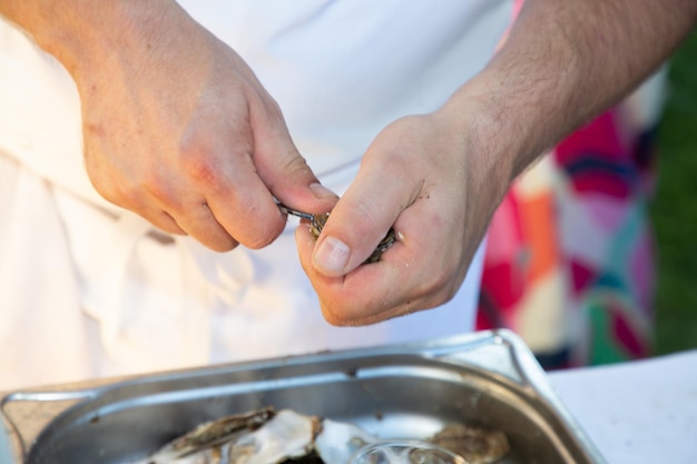 Professionele man chef-kok opent het pellen van oester