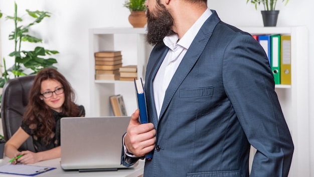 Professionele man in formeel pak bijgesneden weergave staat voor assistent aan het bureau