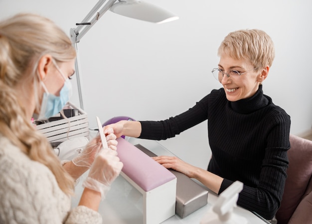 Professionele manicure meester doet nagels voor cliënt in de schoonheidssalon