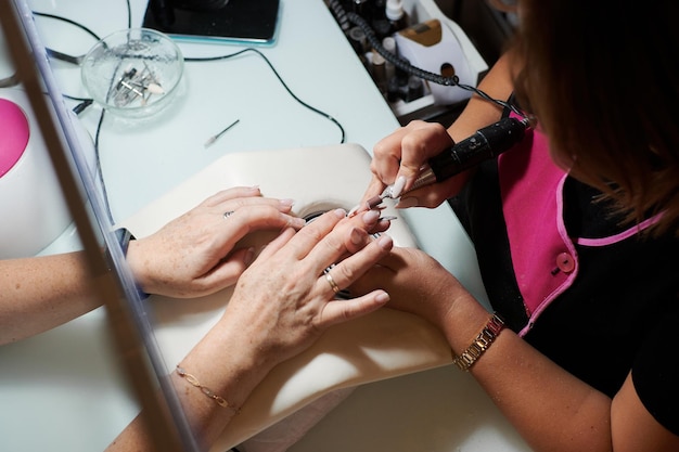 Professionele manicure repareert en verfraait de nagels van een klant