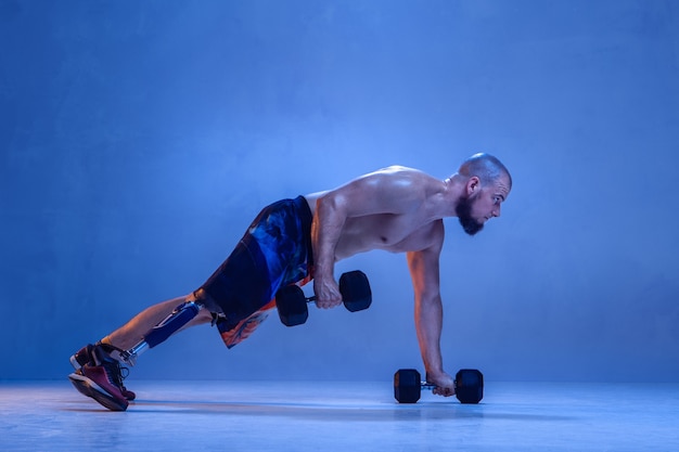 Professionele mannelijke sportman met beenprothese training met dumbbells